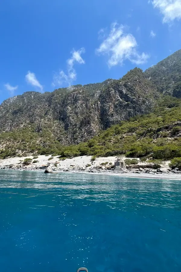Vue panoramique du port et de la plage d'Agios Pavlos, avec les eaux turquoise de la mer Égée en arrière-plan.
