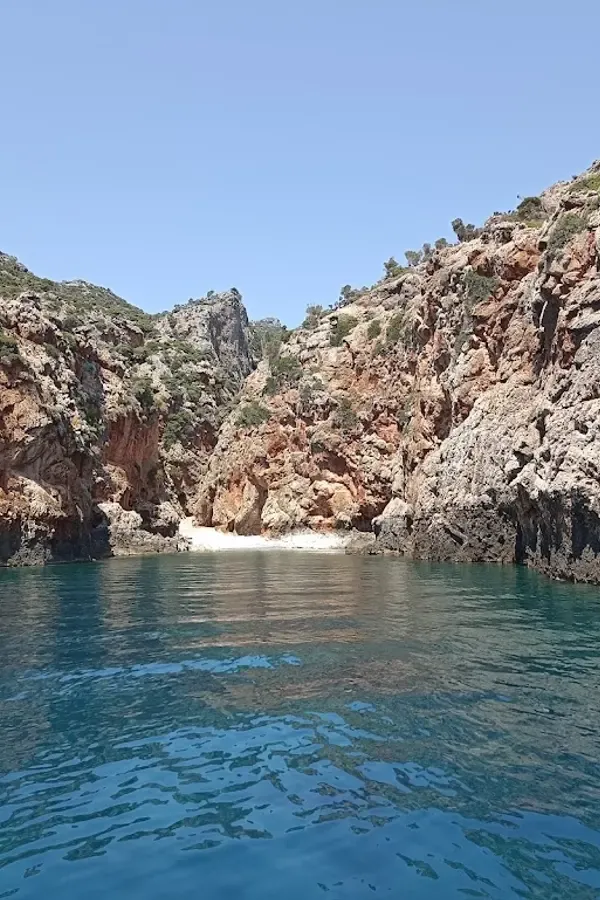 Rugged landscape meeting the calm, deep blue waters at Sfakos beach, Crete.