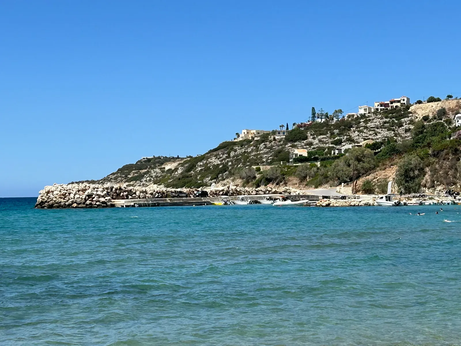 Le pittoresque port d'Almyrida, encadré par des bâtiments colorés et les eaux bleues cristallines de la mer Égée.