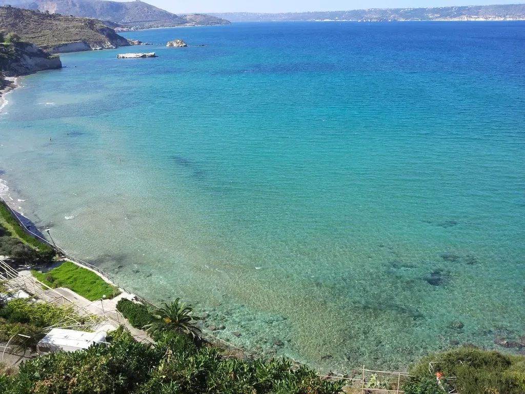 Plage de sable et galets à Kera beach, bordée d'un lagon turquoise et encadrée par des falaises naturelles de la côte de Crète.