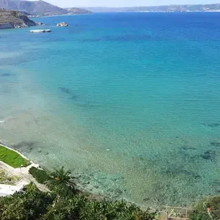Plage de sable et galets à Kera beach, bordée d'un lagon turquoise et encadrée par des falaises naturelles de la côte de Crète.