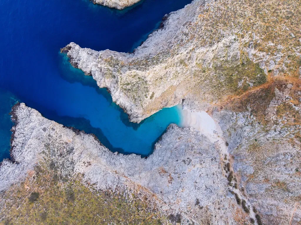 Sur la côte de Seitan Limania, des falaises rocheuses et des criques baignent dans un bleu profond, au bord de la mer Égée.